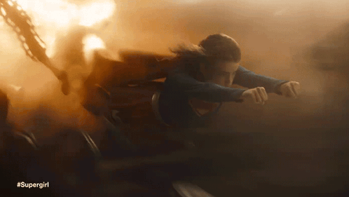 A Woman In A Supergirl Costume Is Flying Through Smoke GIF