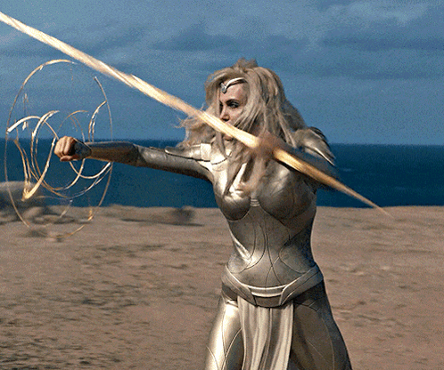 A Woman In A Superhero Costume Holds A Golden Sword GIF