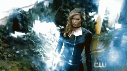 A Woman In A Superhero Costume Is Standing In Front Of A Smokey Background . GIF
