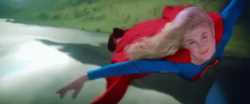 A Woman In A Superman Costume Is Flying Through The Air GIF