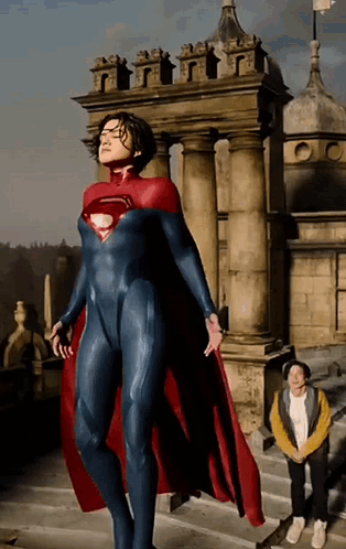 A Woman In A Superman Costume Is Standing In Front Of A Castle GIF