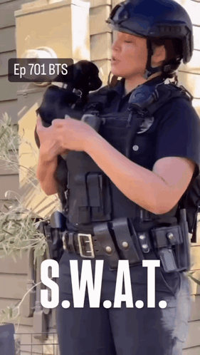 A Woman In A Swat Uniform Holds A Small Dog GIF