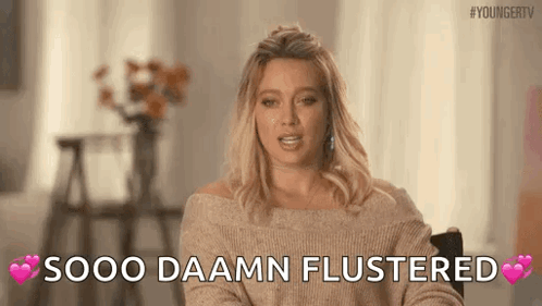 A Woman In A Sweater Is Sitting In A Chair And Says `` Sooo Daamn Flustered '' . GIF