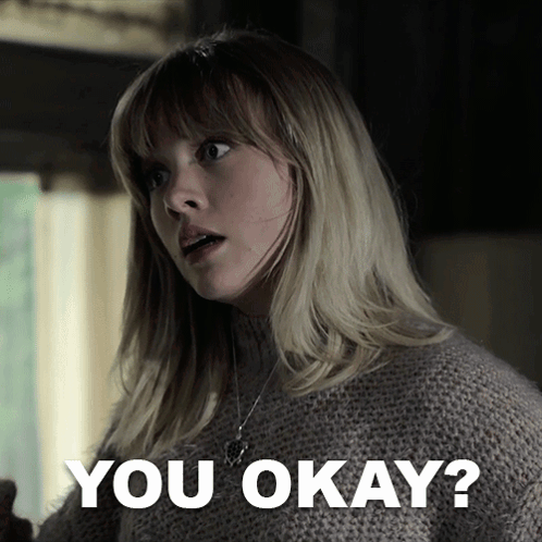 A Woman In A Sweater Says " You Okay " In Front Of Her GIF