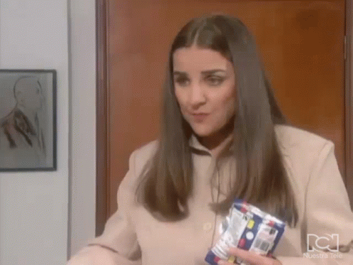 A Woman In A Tan Jacket Is Holding A Can Of Soda In Her Hand . GIF