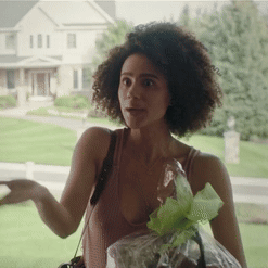 A Woman In A Tank Top Is Holding A Bag Of Grapes GIF