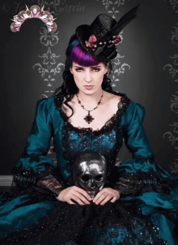 A Woman In A Teal Dress Holds A Skull Mask GIF
