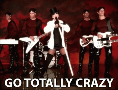 A Woman In A Top Hat Singing In Front Of A Band With The Words Go Totally Crazy Behind Her GIF
