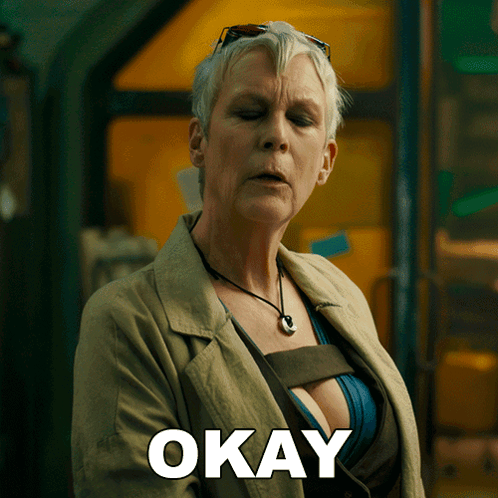 A Woman In A Trench Coat Has The Word Okay Written On Her Chest GIF