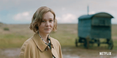 A Woman In A Trench Coat Stands In A Field With A Netflix Logo In The Corner GIF