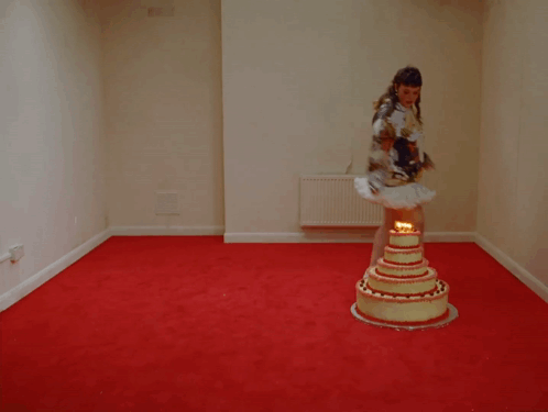 A Woman In A Tutu Stands In Front Of A Cake With Candles On It GIF