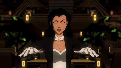 A Woman In A Tuxedo And White Gloves Stands With Her Arms Outstretched In A Dark Room GIF