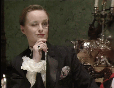 A Woman In A Tuxedo Has A Ring On Her Left Hand GIF