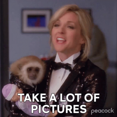 A Woman In A Tuxedo Is Holding A Baby Monkey And Says " Take A Lot Of Pictures " GIF