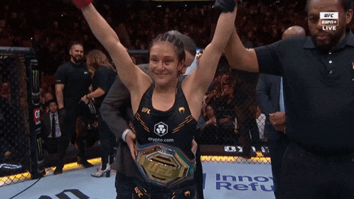 A Woman In A Ufc Championship Belt Holds Up Her Arms GIF