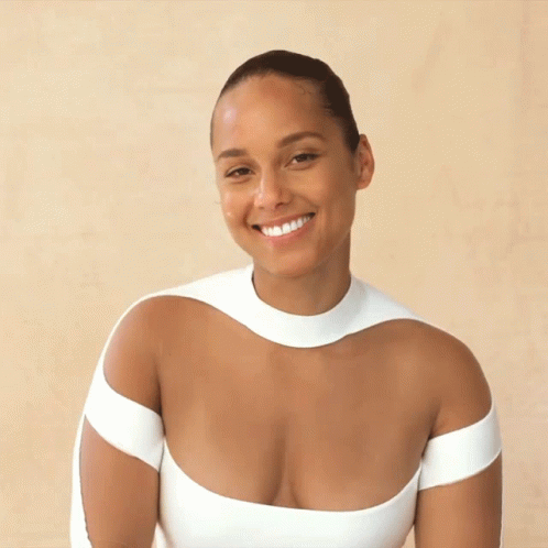 A Woman In A Very Plunging White Top Smiles GIF