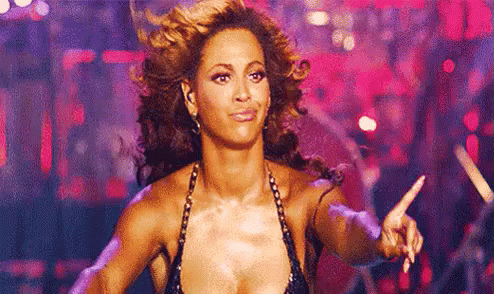 A Woman In A Very Revealing Top Is Dancing On A Stage And Pointing At The Camera . GIF
