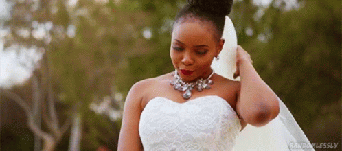 A Woman In A Wedding Dress And Veil Is Standing In Front Of A Forest . GIF