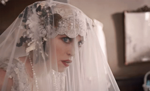 A Woman In A Wedding Dress Has A Veil Over Her Head GIF