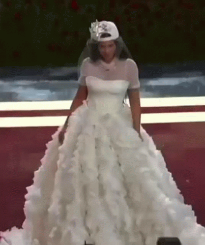 A Woman In A Wedding Dress Is Wearing A Baseball Cap And Veil . GIF