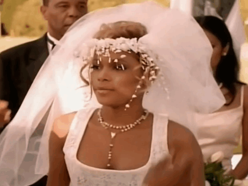 A Woman In A Wedding Dress Is Wearing A Veil And A Flower Crown . GIF