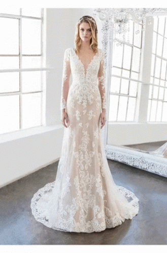 A Woman In A Wedding Dress Stands In Front Of A Mirror GIF