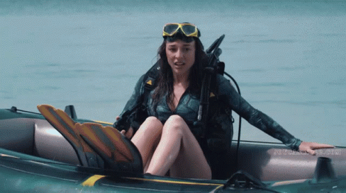 A Woman In A Wet Suit Is Sitting In An Inflatable Boat With The Word Scuba On The Bottom GIF