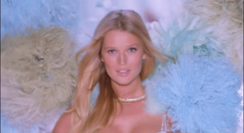 A Woman In A White Bra Is Surrounded By Feathers GIF