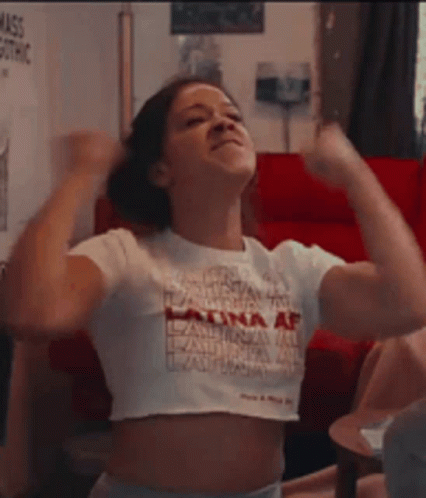 A Woman In A White Crop Top Is Flexing Her Muscles . GIF