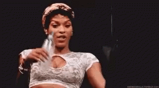 A Woman In A White Crop Top Is Holding A Bottle Of Water In Her Hand . GIF
