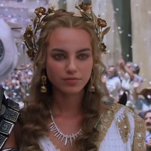 A Woman In A White Dress And A Gold Crown On Her Head . GIF
