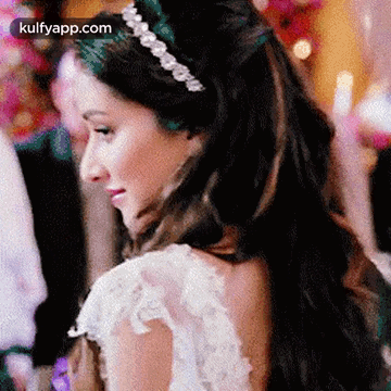 A Woman In A White Dress And A Headband Is Looking Over Her Shoulder . GIF