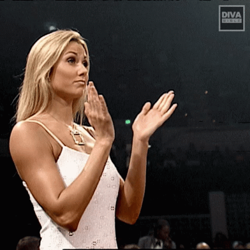 A Woman In A White Dress Applauds In Front Of A Diva Screen GIF