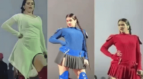 A Woman In A White Dress , Blue Sweater And Red Skirt Is Dancing On A Stage . GIF