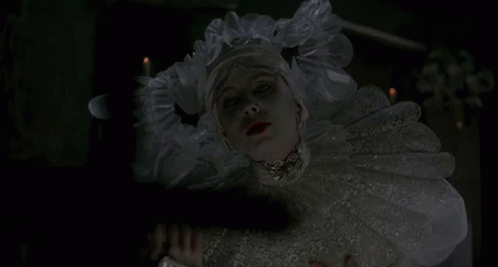 A Woman In A White Dress Holds A Cross In Front Of Her Face GIF
