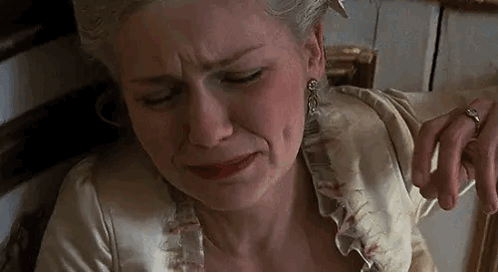 A Woman In A White Dress Is Crying While Sitting On A Bed . GIF