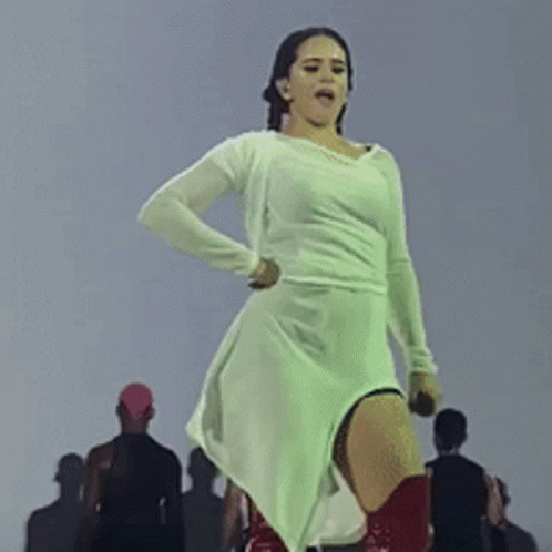 A Woman In A White Dress Is Dancing In Front Of A Crowd GIF