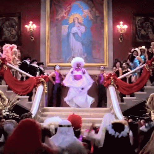 A Woman In A White Dress Is Dancing In Front Of A Large Painting GIF