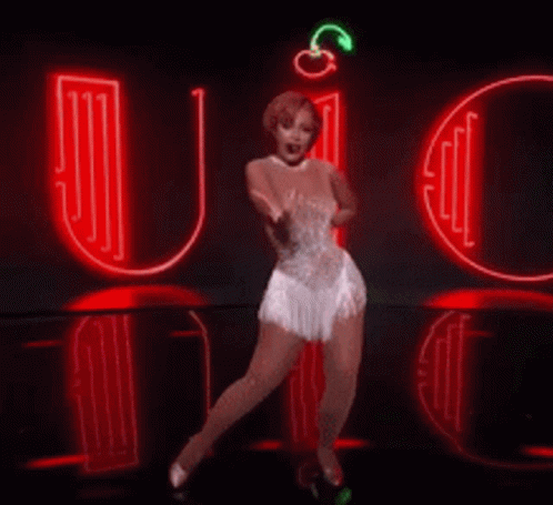 A Woman In A White Dress Is Dancing In Front Of A Neon Sign That Says It 'S Quiet Ain T No Back Talk GIF