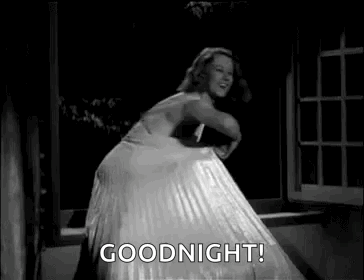 a woman in a white dress is dancing in front of a window and says `` goodnight '' .