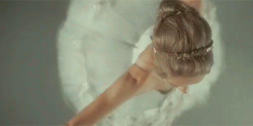 A Woman In A White Dress Is Dancing In The Water . GIF