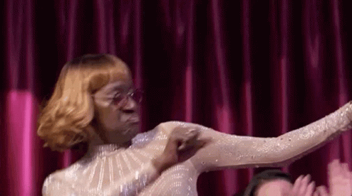 A Woman In A White Dress Is Dancing On A Stage In Front Of A Crowd . GIF
