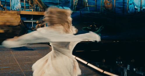 A Woman In A White Dress Is Dancing On A Stage In Front Of A Sign That Says ' Pepsi ' GIF