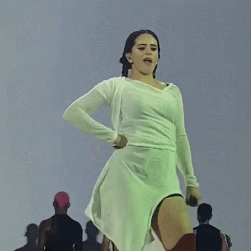 A Woman In A White Dress Is Dancing On A Stage GIF