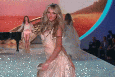 A Woman In A White Dress Is Dancing On The Runway GIF