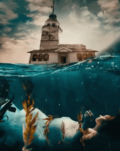 A Woman In A White Dress Is Floating In The Ocean GIF