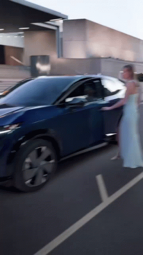 A Woman In A White Dress Is Getting Out Of A Car GIF