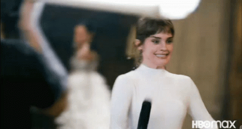 A Woman In A White Dress Is Holding A Microphone . GIF