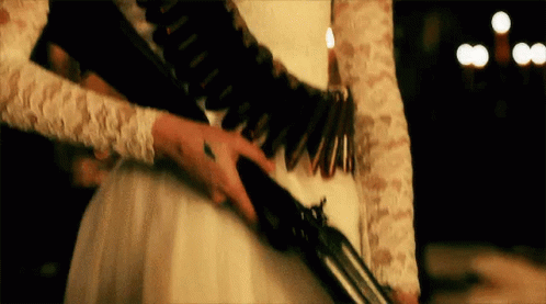 A Woman In A White Dress Is Holding A Shotgun . GIF