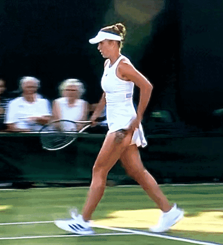 A Woman In A White Dress Is Holding A Tennis Racket On A Tennis Court GIF